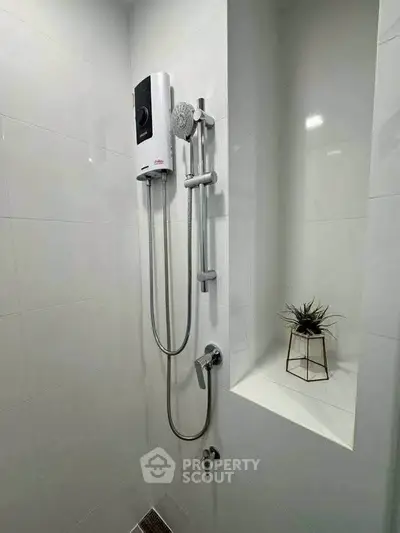 Modern bathroom shower area with sleek fixtures and a small decorative plant.