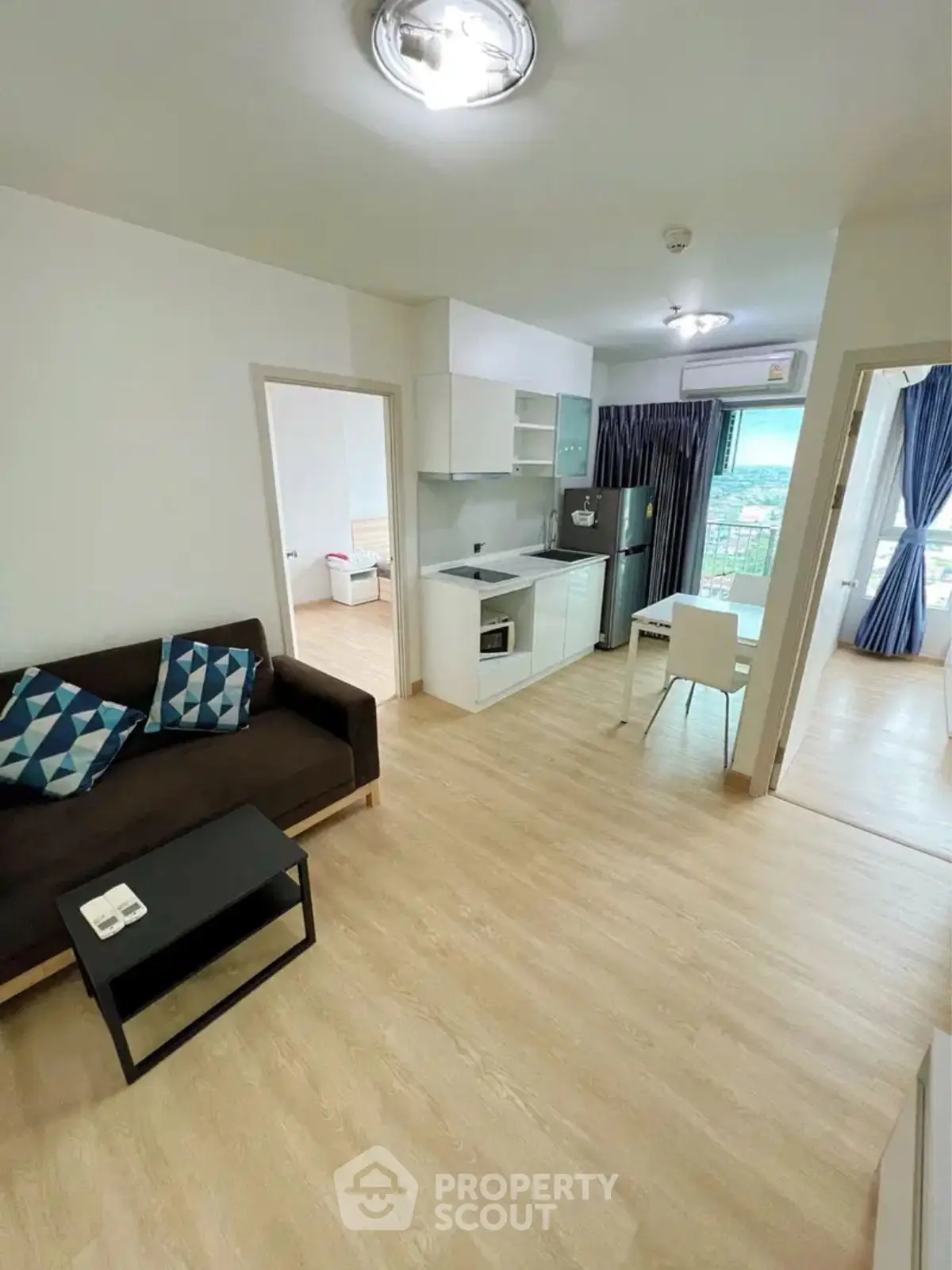 Modern open-plan living room with kitchen and dining area, featuring sleek design and natural light.