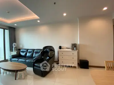 Modern living room with sleek black leather sofa and massage chair, featuring elegant lighting and minimalist decor.