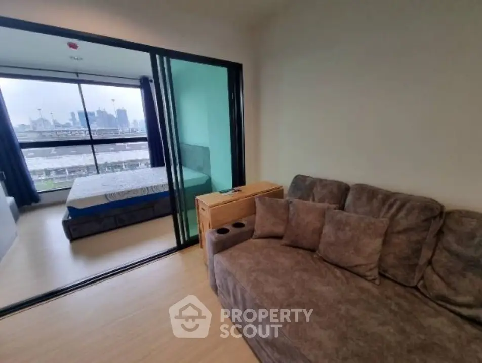 Modern apartment with cozy living room and bedroom, featuring large windows and city view.