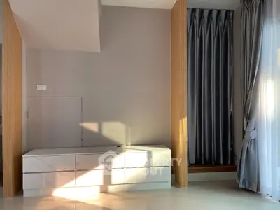 Modern interior with sleek white cabinetry and elegant floor-to-ceiling curtains in a sunlit room.