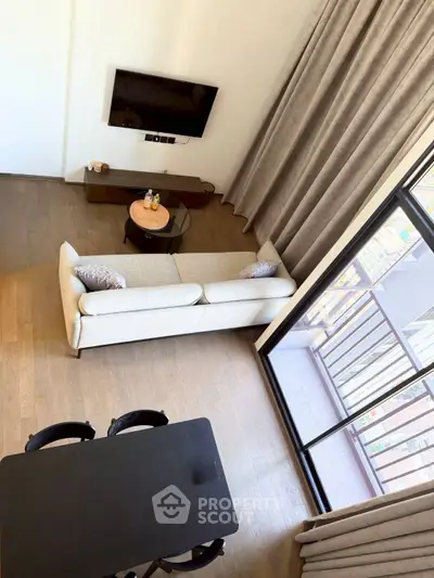 Modern living room with balcony view, featuring sleek furniture and floor-to-ceiling curtains.