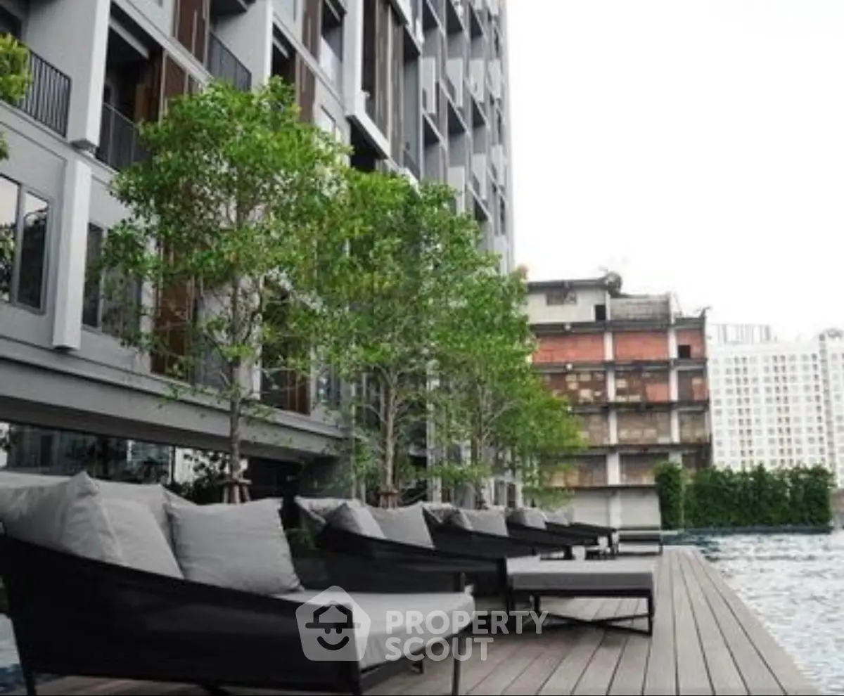 Luxurious apartment building with poolside lounge area and city view.