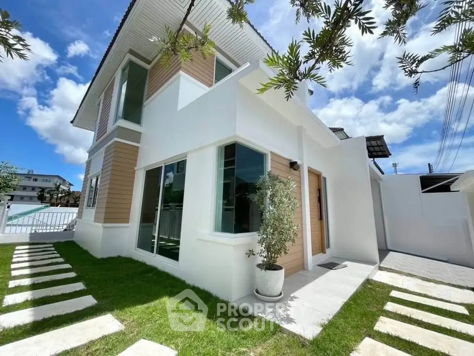 Modern two-story house with lush green lawn and stylish exterior design under a clear blue sky.