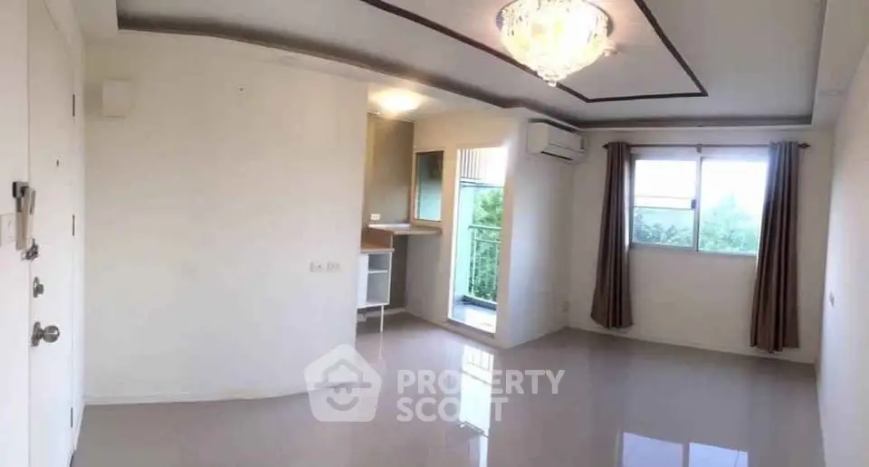 Spacious living room with chandelier and balcony access in modern apartment.
