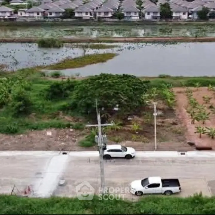 Scenic view of residential area with lush greenery and serene water body, ideal for tranquil living.