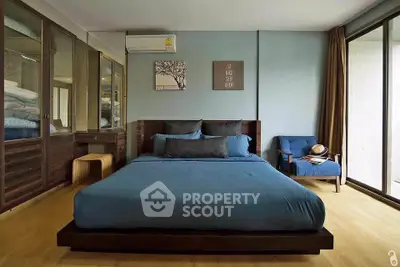 Spacious bedroom with modern decor and large windows for natural light.