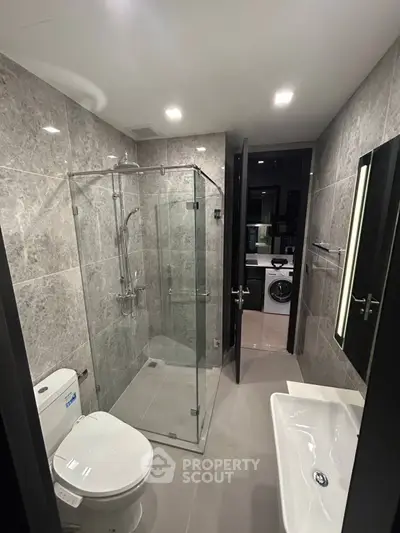 Modern bathroom with glass shower and sleek fixtures in contemporary apartment.