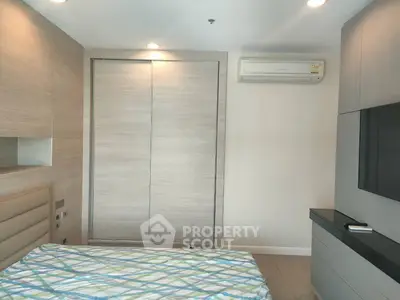 Modern bedroom with sleek design, featuring built-in wardrobe and air conditioning unit.