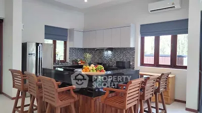 Modern kitchen with island, wooden chairs, and stainless steel appliances