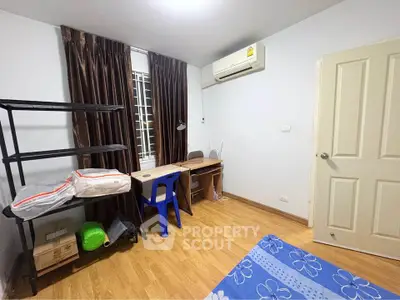 Cozy bedroom with study area, air conditioning, and wooden flooring in modern apartment.