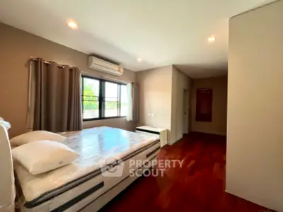 Spacious bedroom with hardwood floors and large window for natural light