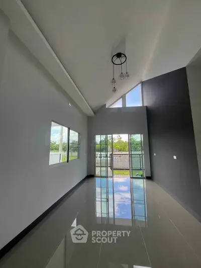 Spacious modern living room with high ceiling and large windows offering natural light.