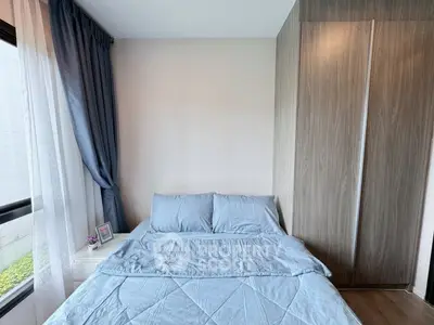 Cozy bedroom with blue bedding and large window, featuring modern wardrobe.
