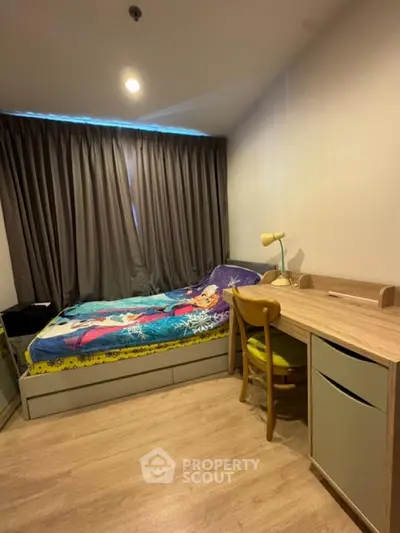 Cozy bedroom with modern desk and stylish bedding in a well-lit apartment.