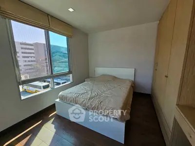 Cozy bedroom with large window and built-in wardrobe in modern apartment