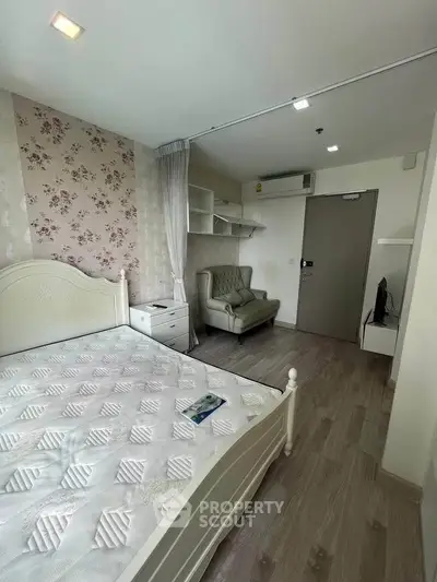 Charming bedroom with floral accent wall and cozy seating in modern apartment.