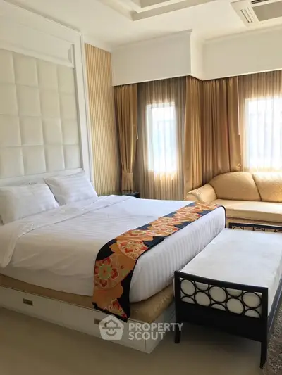 Luxurious bedroom with elegant decor and natural light, featuring a cozy bed and stylish seating area.