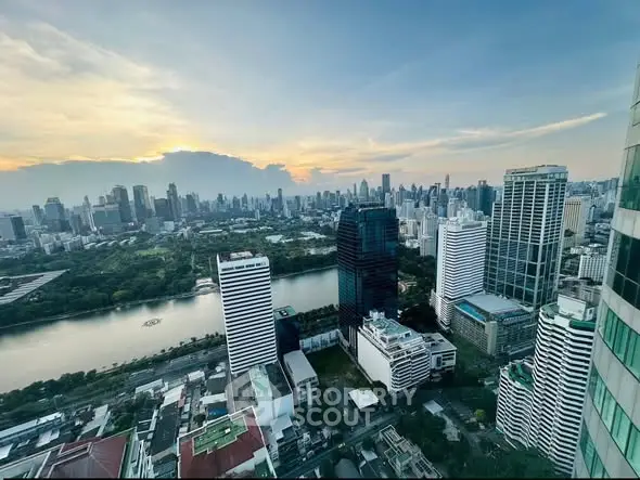 Stunning cityscape view from high-rise building overlooking river and skyline at sunset.