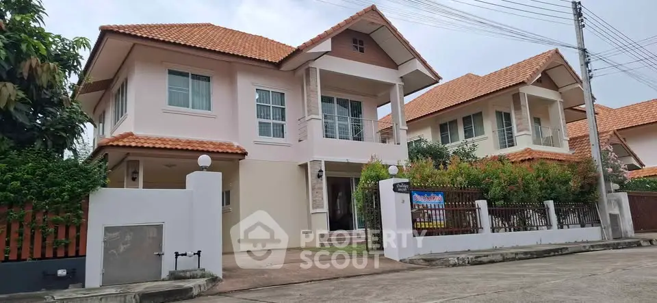 Charming two-story house with red-tiled roof and lush garden in a serene neighborhood.