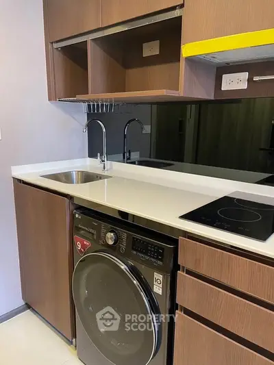 Modern kitchen with sleek cabinetry, integrated washing machine, and electric cooktop.
