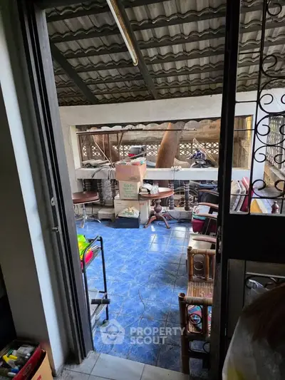 Charming covered outdoor space with blue tiled flooring and rustic furniture, perfect for relaxation.