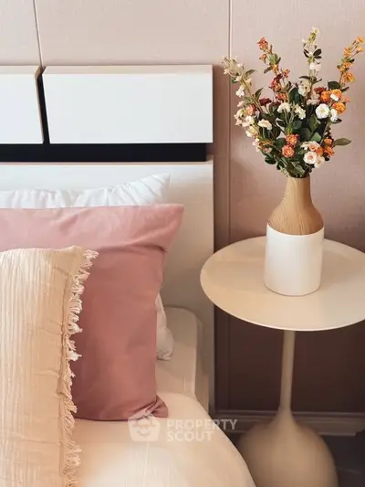 Elegant bedroom with stylish decor and floral arrangement on a modern side table.