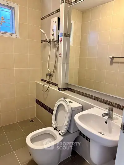 Modern bathroom with sleek fixtures and neutral tiles, featuring a shower and toilet.