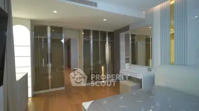 Luxurious modern bedroom with sleek glass wardrobe and elegant wooden flooring.