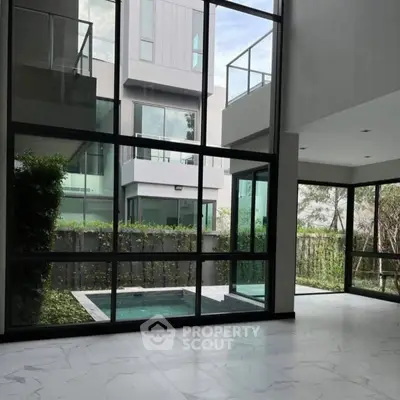 Modern home interior with large windows and pool view, showcasing sleek design and natural light.