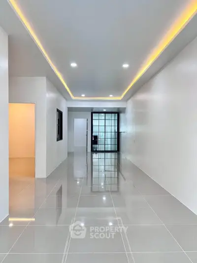 Spacious modern living room with sleek tile flooring and ambient ceiling lighting.