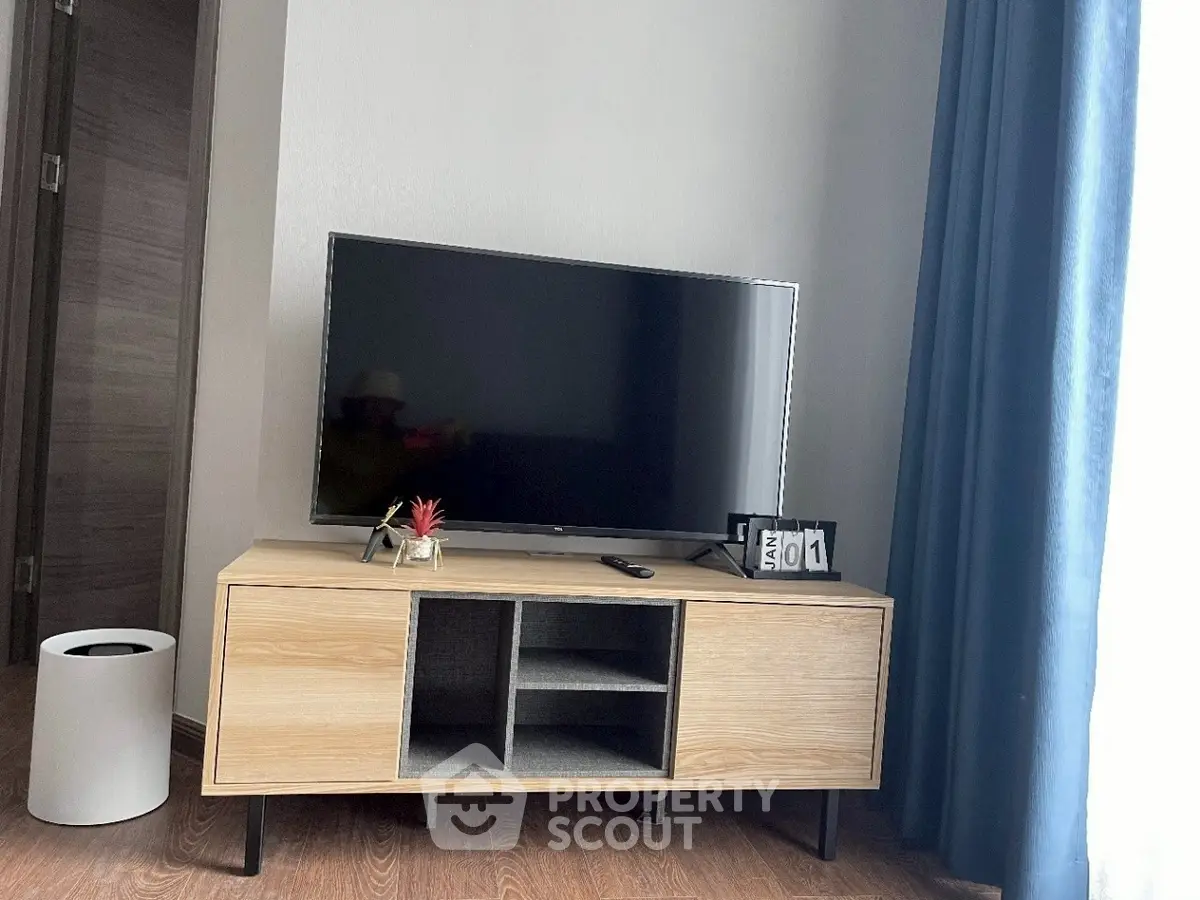 Modern living room with stylish TV stand and flat-screen TV, complemented by elegant curtains.