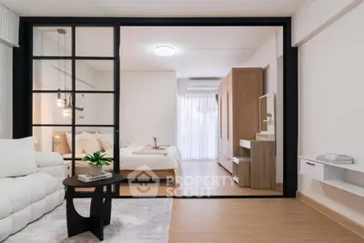 Modern open-plan living room with sliding glass doors leading to a cozy bedroom, featuring stylish decor and natural light.