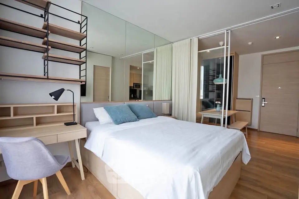 Modern bedroom with stylish decor, featuring a cozy bed, desk, and open shelving, perfect for urban living.