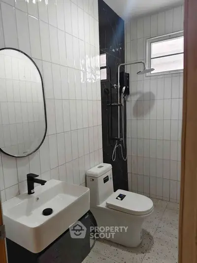 Modern bathroom with sleek fixtures and contemporary design, featuring a shower and stylish sink.