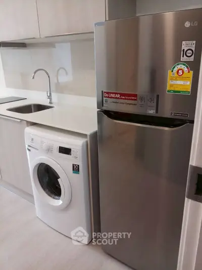 Modern kitchen with sleek appliances including fridge and washing machine