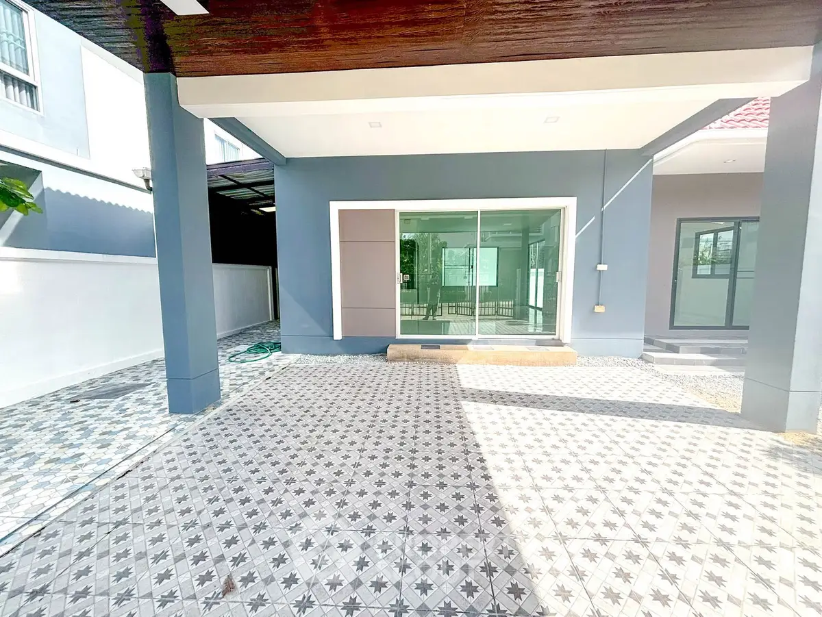 Modern house exterior with spacious tiled patio and large glass doors.