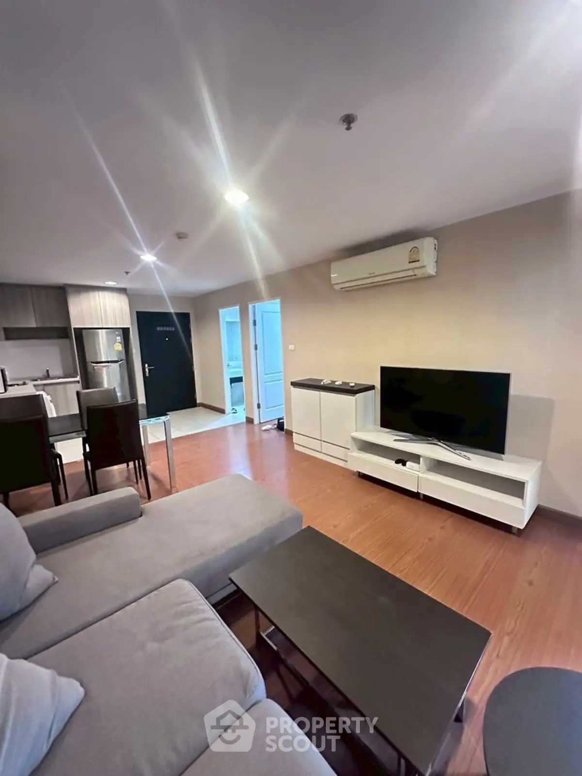 Modern living room with open kitchen, featuring sleek furniture and contemporary design.