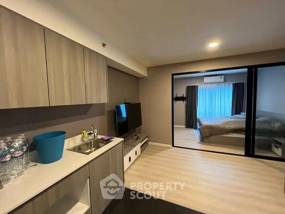 Modern studio apartment with open layout, featuring a cozy living area and bedroom separated by glass doors.