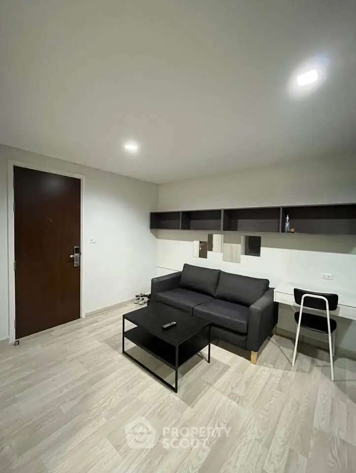 Modern living room with sleek black sofa, stylish shelving, and minimalist decor.