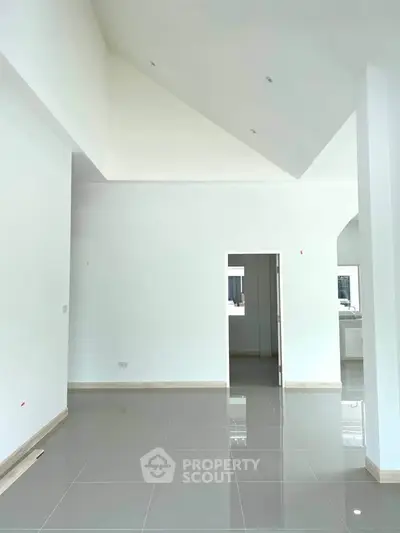 Spacious modern interior with high ceilings and glossy tiled floors, perfect for contemporary living.