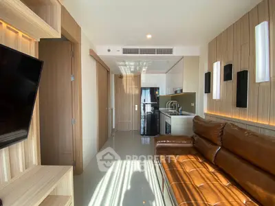 Modern living room with sleek design and open kitchen layout, featuring leather sofa and stylish lighting.