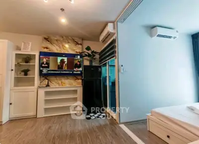 Modern living room with stylish decor and air conditioning, featuring a large TV and sliding glass doors.