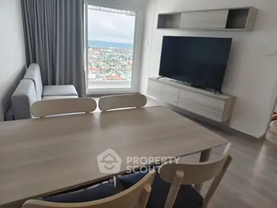 Modern living room with large window and city view, featuring sleek furniture and a flat-screen TV.