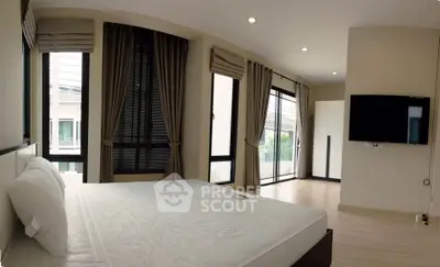 Spacious modern bedroom with large windows and wall-mounted TV
