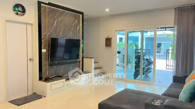 Modern living room with sleek TV setup and glass doors leading to patio