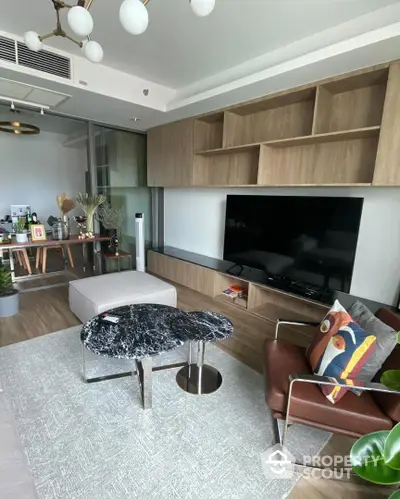 Chic and modern living space with sleek wooden cabinetry, plush leather sofa, and a stylish marble-top coffee table, complemented by an open-plan kitchen.