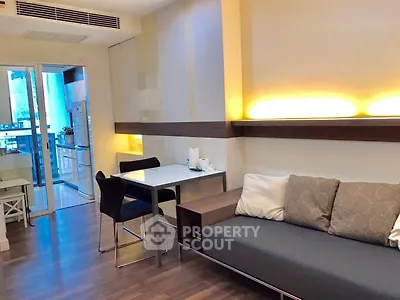 Modern living room with sleek furniture and open kitchen layout in urban apartment.