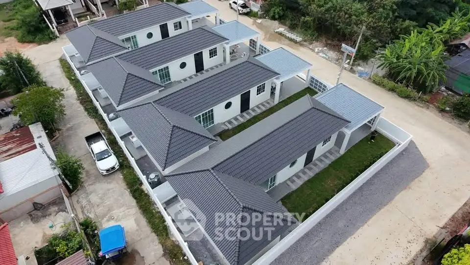 Aerial view of modern residential complex with sleek rooftops and private driveways.