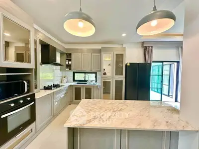 Modern kitchen with marble island, sleek cabinetry, and large windows for natural light.